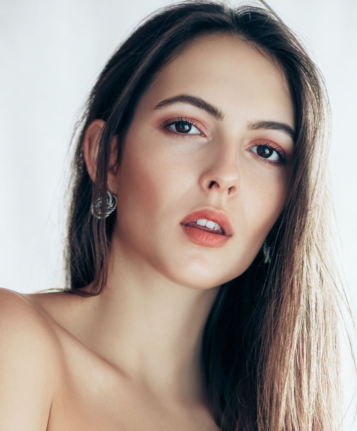 Smiling woman with curly hair and necklace.